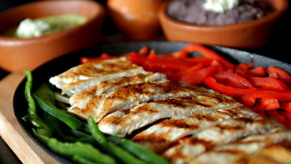 Delicious grilled chicken fajitas with bell peppers, served with traditional Mexican sauces.